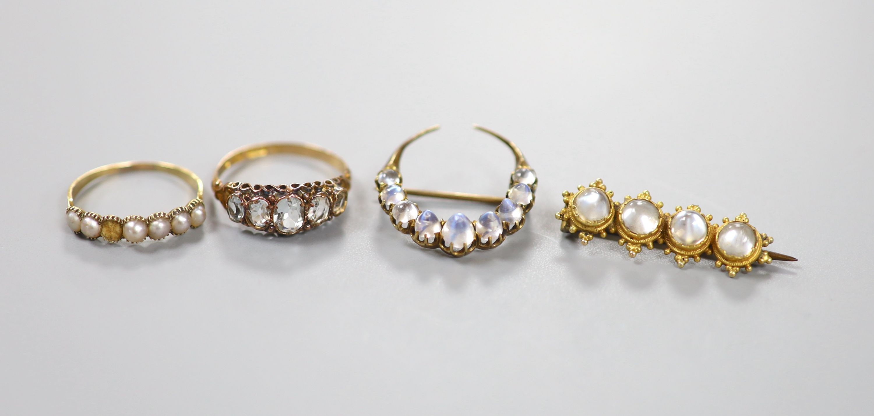 A Victorian 15ct gold and graduated aquamarine set half hoop ring, size O, gross 1.8 grams, a split pearl set ring(a.f.) and two antique yellow metal and moonstone set brooches, including crescent, gross 6.4 grams.